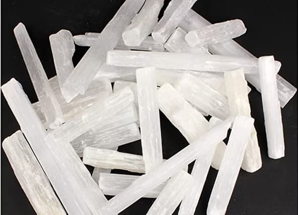 A pile of translucent white crystalline sticks on a dark background.