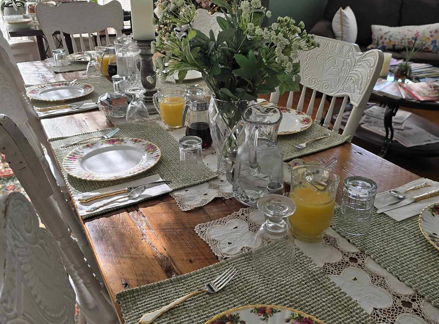 A beautifully set dining table with flower arrangements, plates, and drinks.