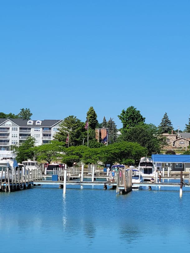 A marina with boats docked alongside a waterfront hotel under a clear blue sky.